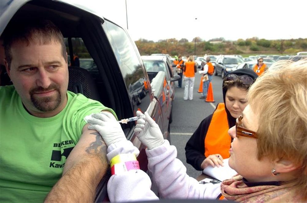 Greg Kerchner of Northampton, receives a flu shot while sitting in his pick up truck from Katy Piokowski during the Lehigh Valley Hospital Drive Thru Flu Shot Clinic on Sunday in Bethlehem, Pa.