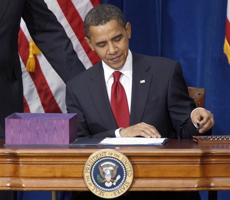 President Barack Obama picks up the first pen to sign the economic stimulus bill during a ceremony on Tuesday in the Museum of Nature and Science in Denver.