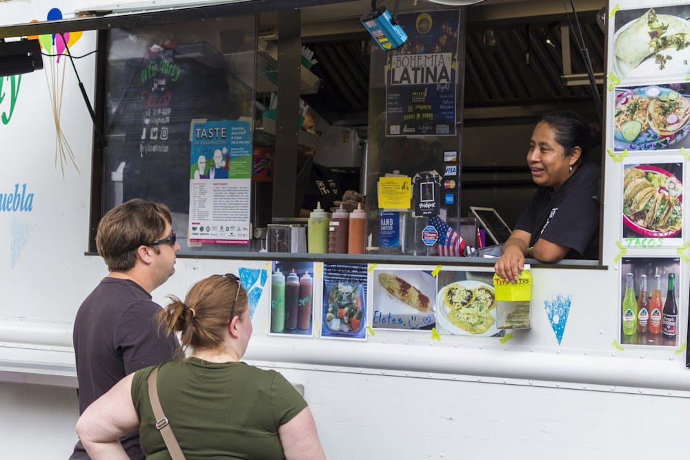 2018年6月23日，参加第36届布鲁明顿美食节的人们从Pili 's Party Taco卡车上的一名员工处订餐。今年的Taste of Bloomington将被6月20日至26日为期一周的“Taste to - go”活动所取代。