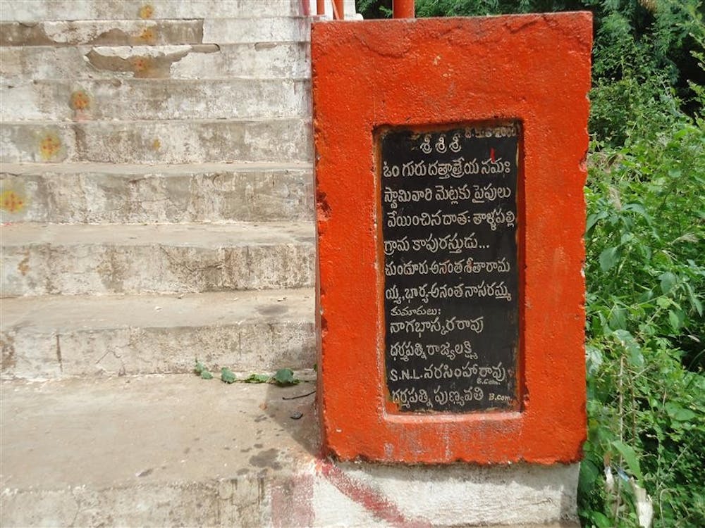 A sign in Telegu directs visitors up the stairway to a Hindu temple by Ethipothala Falls.
