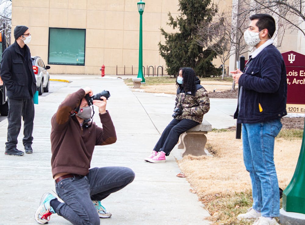 <p>Senior Max Eslava poses as junior Tyler Richardson takes a picture for their photography class Monday outside of the IU Fine Arts Building. IU students started in-person classes Monday after having virtual classes since Jan. 19.  </p>