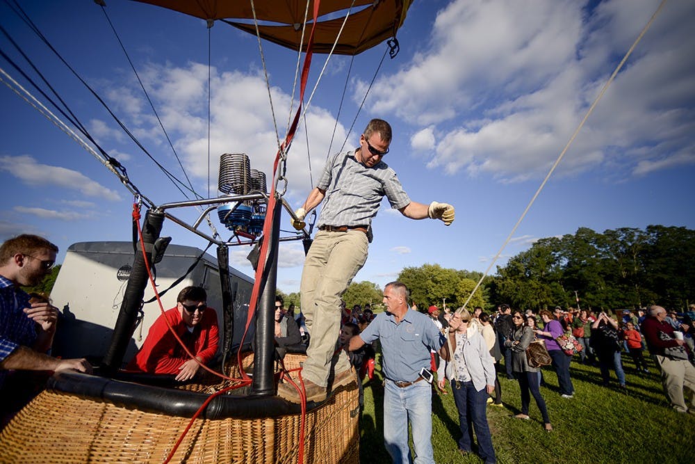 Before flying in the 2014 Kiwanis Balloon Festival, Bill Oliver stands on the basket to keep the balloon on the ground.