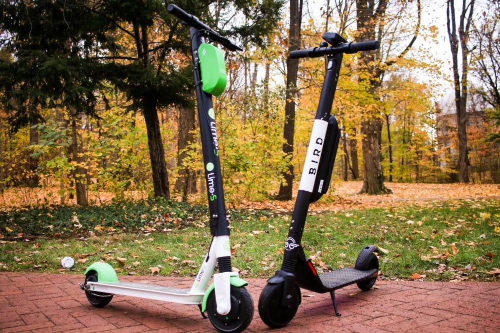 <p>A Bird and Lime scooter are set across from each other in front of Dunn's Woods. Bird and Lime electric scooter companies signed an agreement with the City of Bloomington on Wednesday to continue using the city’s parks and right-of-way to operate their businesses.</p>