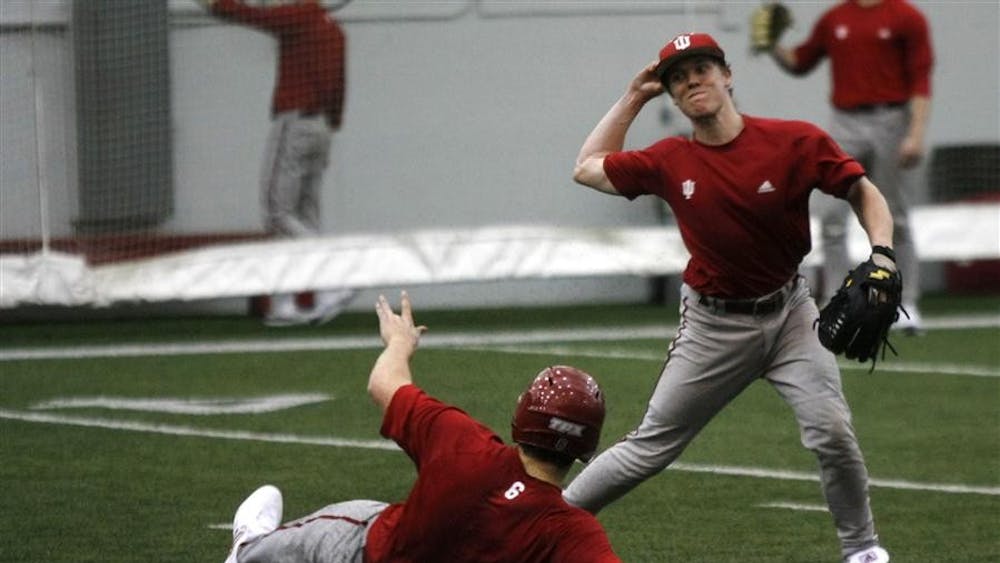 Freshman Chad Clark tries to throw out a runner at first base during practice Tuesday at John Mellencamp Pavilion.
