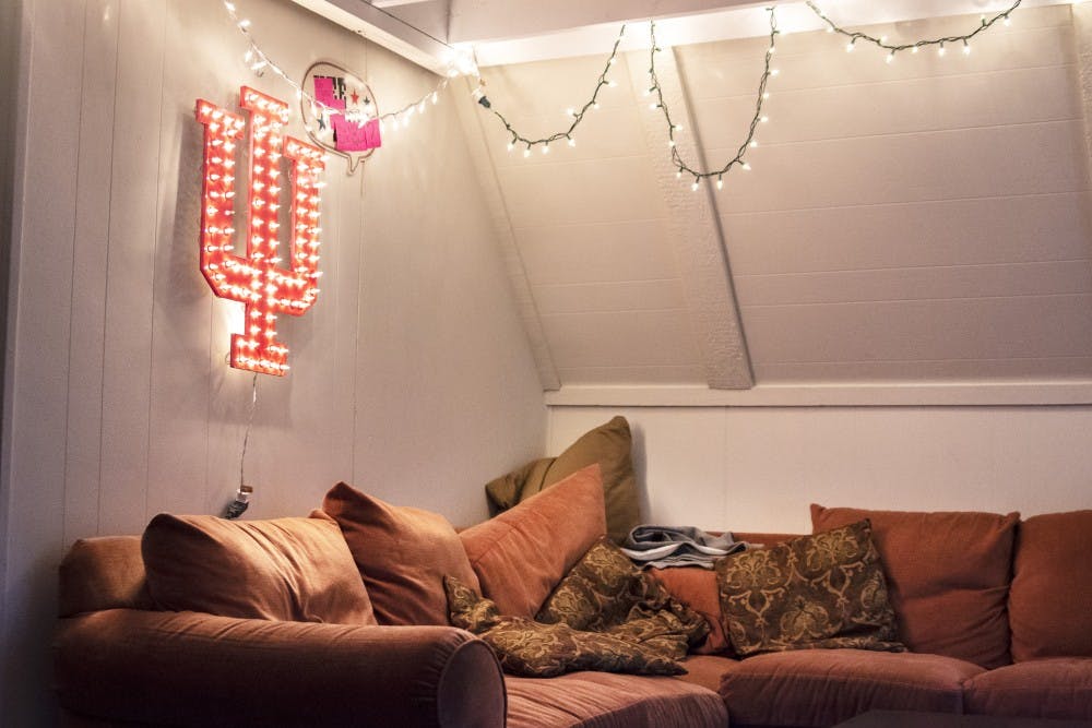 Lights and an illuminated IU sign hang in the living room of an off-campus house in Bloomington.
