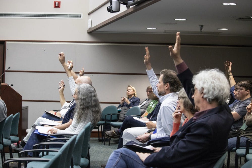 <p>Bloomington residents raise their hands April 17 during the Bloomington City Council meeting in City Hall. People were raising their hand to say they wanted to speak during public comment.</p>