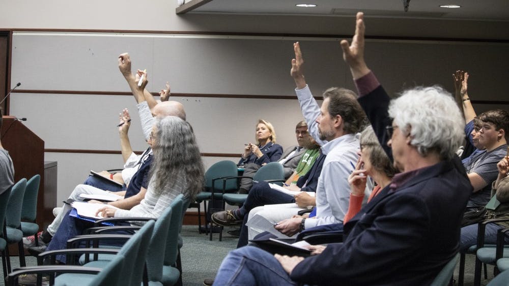 Bloomington residents raise their hands April 17 during the Bloomington City Council meeting in City Hall. People were raising their hand to say they wanted to speak during public comment.