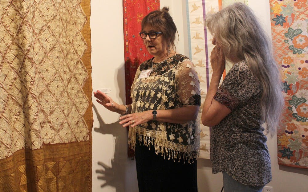 Collector Suzanne Halvorson, left, tells Margie VanAuken about a piece on display at the Ivy Tech John Waldron Center during the Bloomington Gallery Walk. The exhibit for the 23rd Lotus World Music & Arts Festival focused on pieces worn around the world from the 1700s to contemporary times.