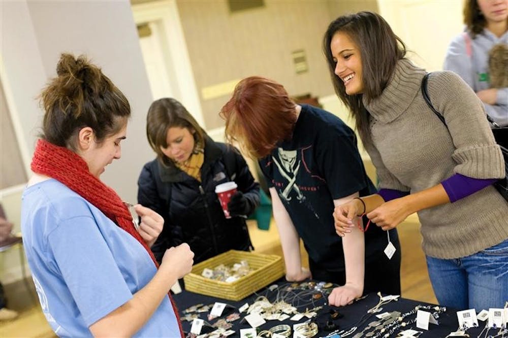 Fair Trade volunteer Julia Greenwald, left, displays jewelry to senior Julia Ellis during a sale held by Fair Trade Bloomington on Thursday afternoon in the Indiana Memorial Union Georgian Room. The sale contained many types of goods from cultures around the world.