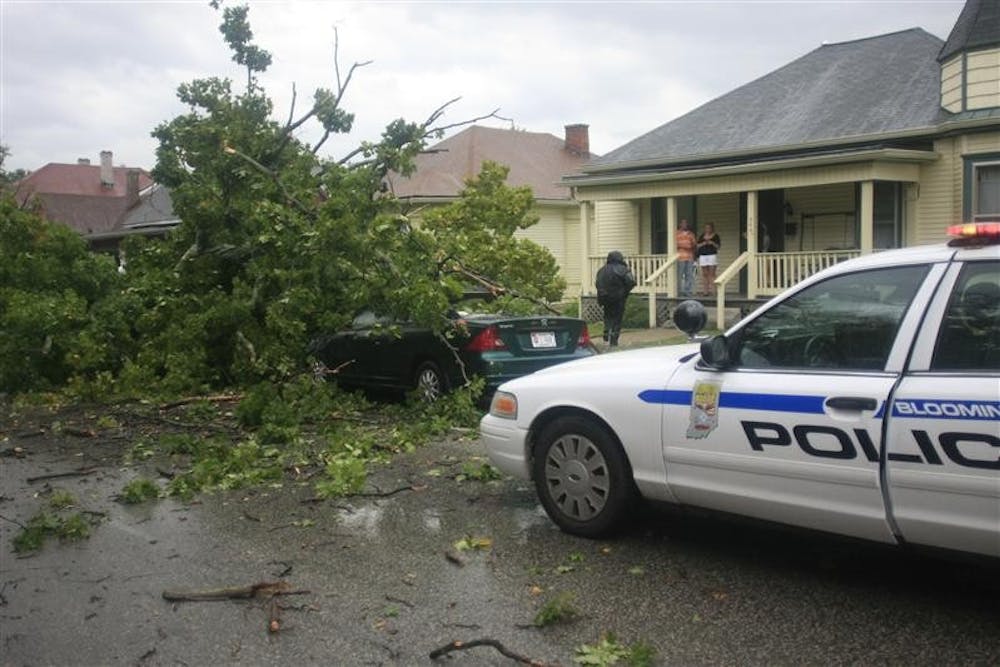 Bloomington Police Department officer Amy Myers speaks with senior Tara Garrett after a tree fell on her car Sunday afternoon at Sixth and Grant Streets.