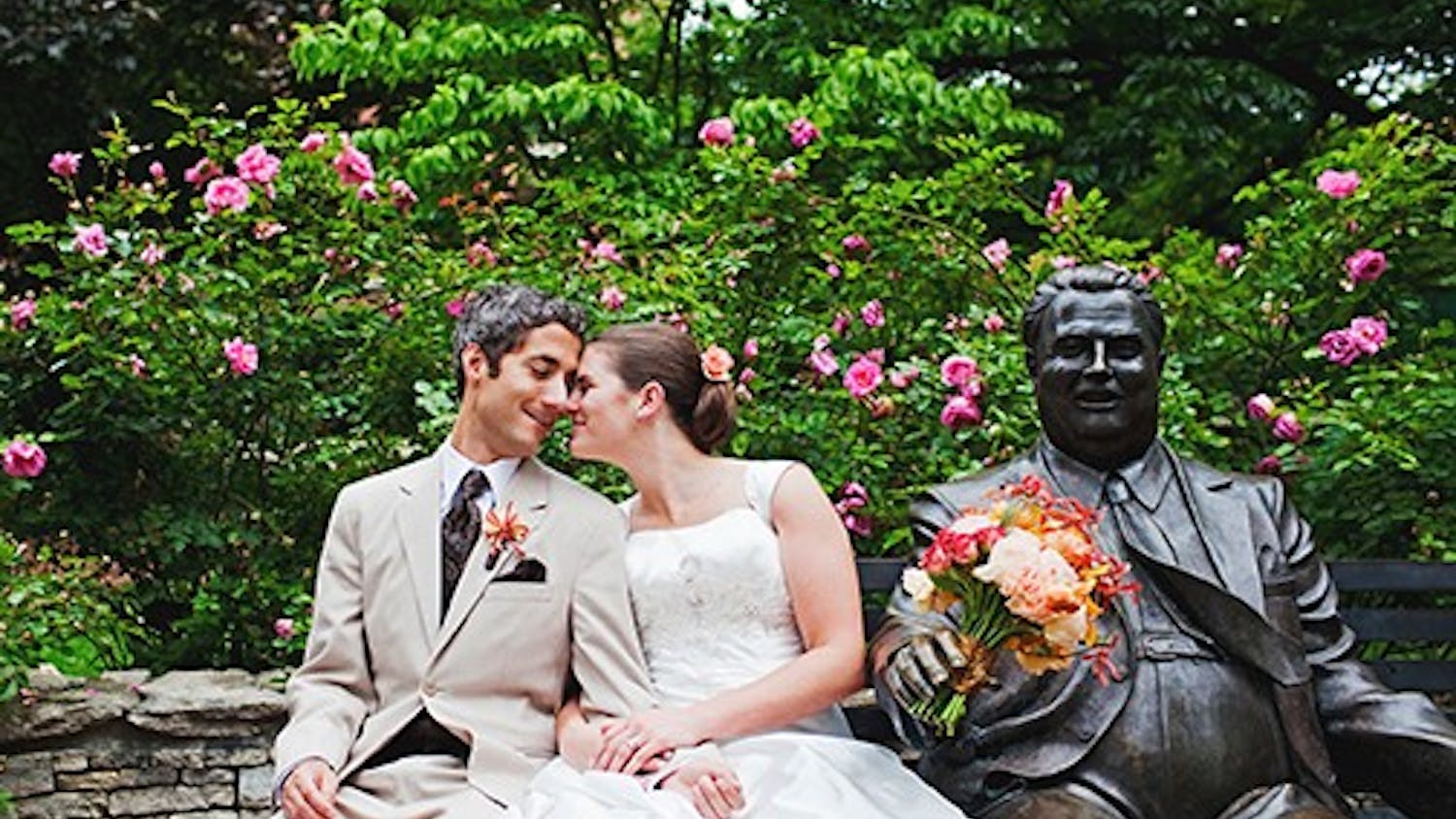 Katie Yoder and her new husband sit next to the statue of Herman B. Wells. Wendi Chitwood, their photographer, frequently incorporates IU Bloomington landmarks into her photos.