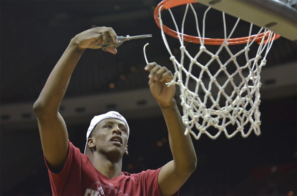 Junior guard Troy Williams cuts the net after finishing the regular season on Sunday at the Assembly Hall. 
