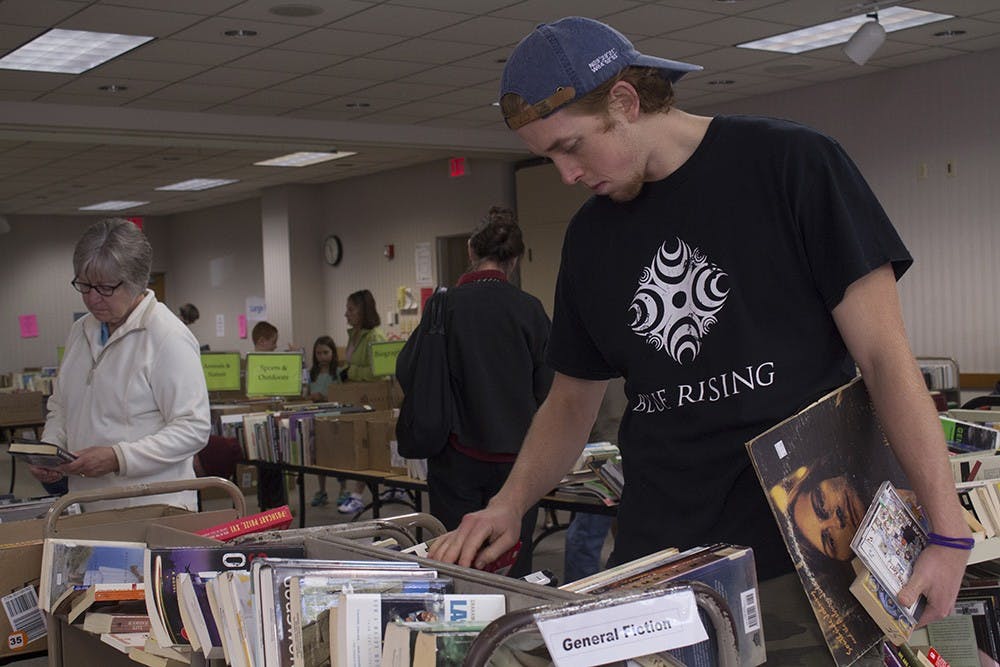 Bloomington resident Adam Sowder looks through a stack of fiction novels during the Friends of the Library Clearance on Monday at Monroe County Public Library.