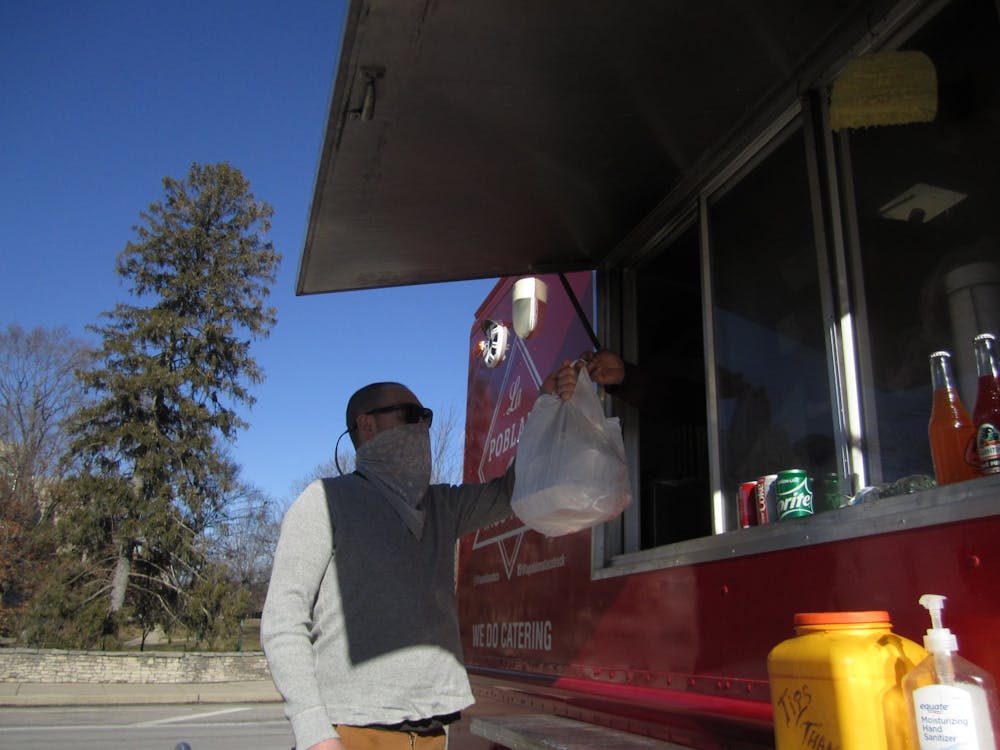 <p>Brown County resident Jacob Ebel receives food from the La Poblana food truck parked in the TIS parking lot Jan. 19. La Poblana is one of many food trucks in Bloomington whose sales drop during the winter months. </p>