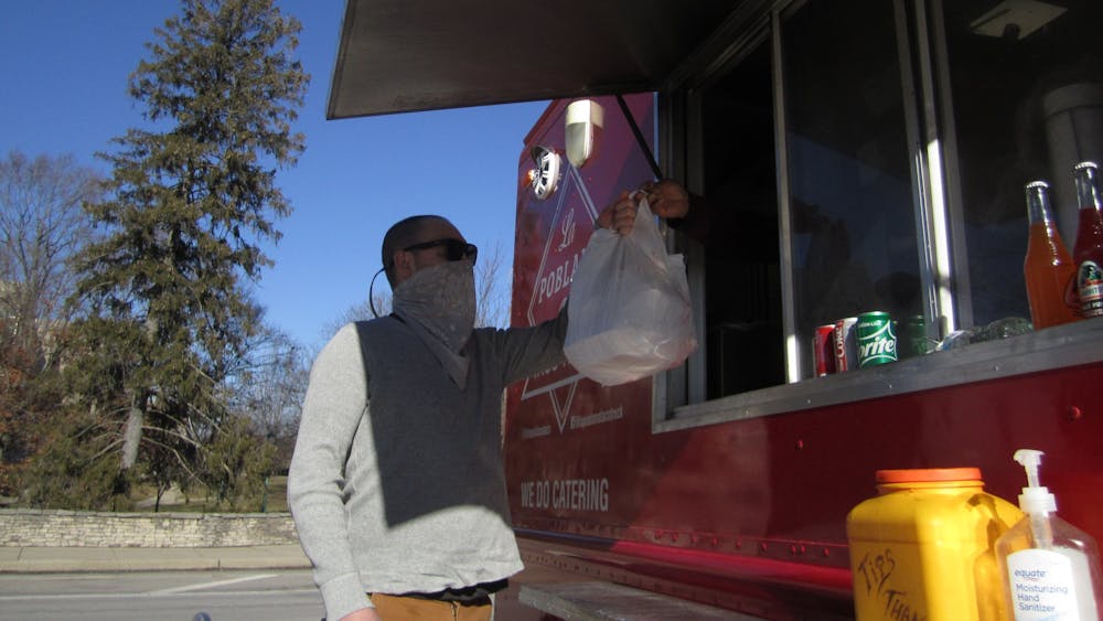 1月19日，布朗县居民雅各布·埃贝尔(Jacob Ebel)从停在塔斯马尼亚大学(TIS)停车场的La Poblana食品卡车上领取食品。La Poblana是布鲁明顿许多冬季销量下降的快餐车之一。