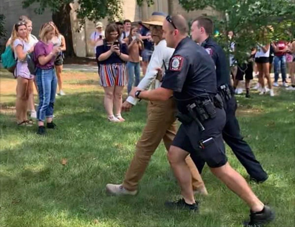 <p>Brother Jed is led away by IU Police Department officers ﻿Sept. 11 outside Woodburn Hall. Students in the crowd shouted questions back and took photos while he preached. The 76-year-old preacher, whose real name is George Smock, was issued a trespass warning after allegedly pushing a man. </p><p><em>CORRECTION: A previous version of this caption stated Brother Jed was led away in handcuffs, and issued a trespass warning after pushing a man. The IDS regrets this error.</em></p>