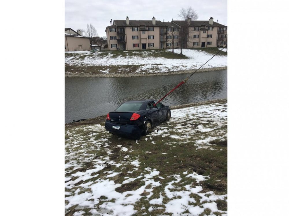 The Indianapolis Fire Department pulls a navy-blue Pontiac G6 out of a retention pond. Anthony Burgess Jr. died Sunday after saving his three-year-old daughter from their sinking car, which fell into the retention pond at the Core Riverbend apartments after his daughter had accidentally bumped the gear shift when climbing into the front seat. 