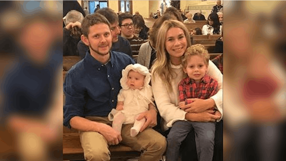 Parents Aaron and Desiree Csikos hold their children Emma and Aaron Jr. during Emma&#x27;s christening ceremony. Desiree&#x27;s two children can’t stay with or visit her in the hospital due to the possibility of contracting or bringing in the virus.