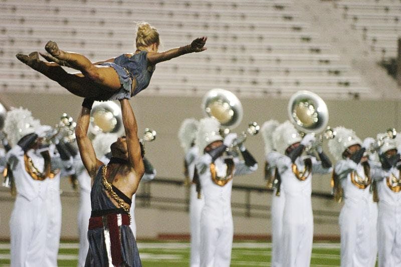 A member of the Phantom Regiment colorguard is hoisted by a fellow member during Friday evening's DCI World Class Semifinals event at Memorial Stadium. Phantom moved into 2nd place heading into Saturday's DCI World Class Finals.