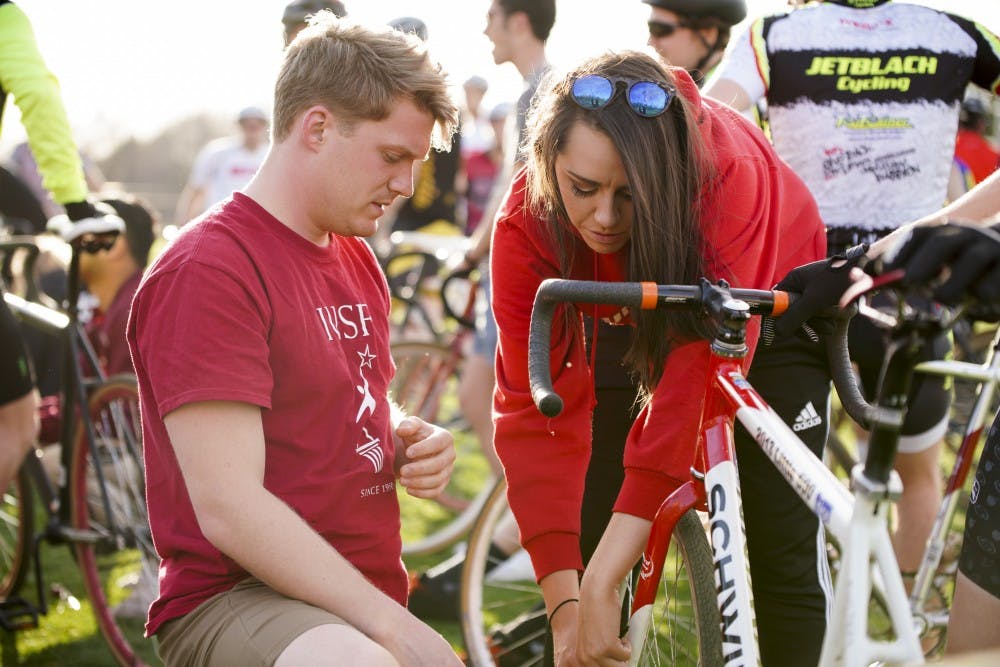 <p>IU Student Foundation members Michael Naughtin and Harvest Ham chip bikes to track and time riders during the practice session for Little 500 on Thursday evening at Bill Armstrong Stadium.</p>