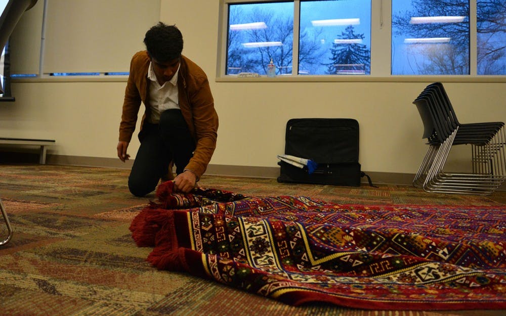 Sophomore Faadil Shariff lays down prayer rugs before the "Taste of Islam" banquet Thursday night. "Taste of Islam" is the fourth of five events for the Muslim Student Association's Islam Awareness Week.