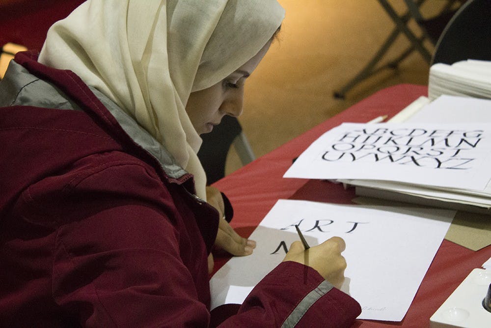 Nouf Kurdi, an Ivy Tech student, volunteers at the calligraphy station of the IU Art Museum's MIX: Pride and Prejudice on Thursday. The event was in conjuction with the IU Department of Theatre and Drama's production of Pride and Prejudice.