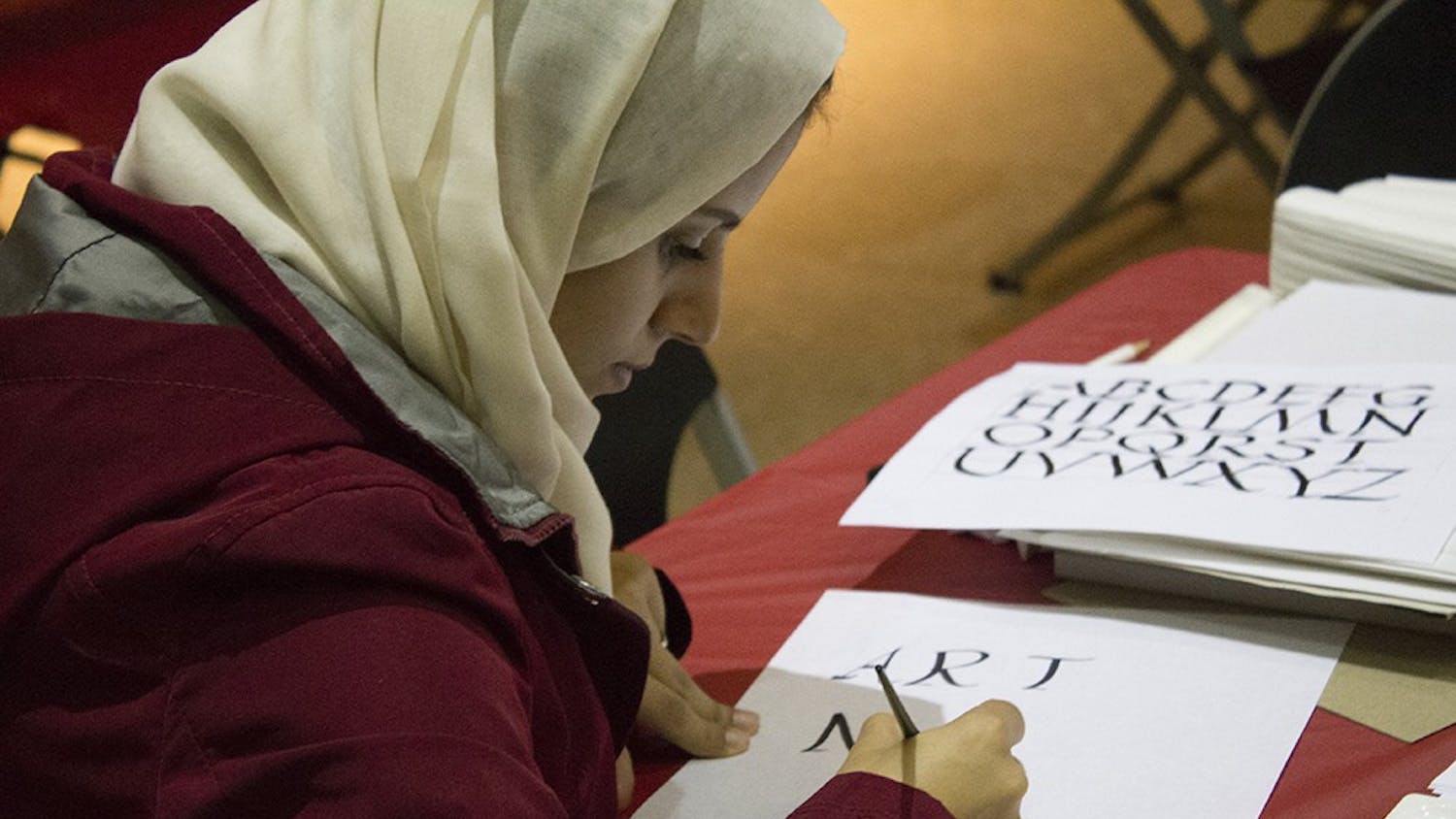Nouf Kurdi, an Ivy Tech student, volunteers at the calligraphy station of the IU Art Museum's MIX: Pride and Prejudice on Thursday. The event was in conjuction with the IU Department of Theatre and Drama's production of Pride and Prejudice.
