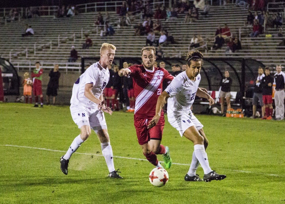 <p>Sophomore Spencer Glass, center, runs the ball through Northwestern players Mac Mazzola, left, and Julian Zighelboim, right, Sept. 26 at Bill Armstrong Stadium. Glass’ run resulted in IU’s second goal of the night with Griffin Dorsey connecting with the ball in front of net to finish the game against NU, 2-1.</p>