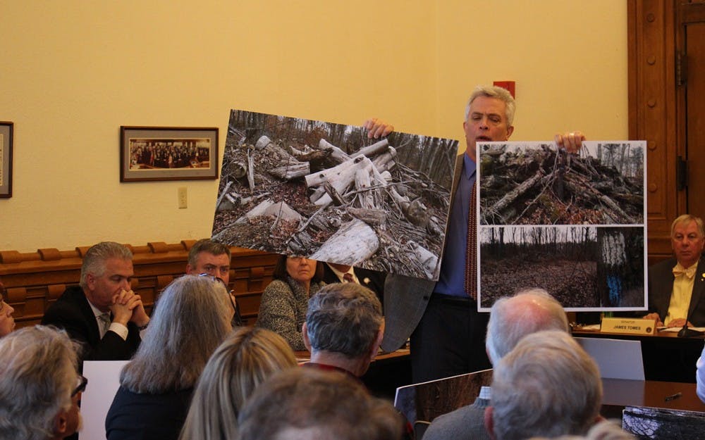 Jeff Stant, executive director of the Indiana Forest Alliance holds up posters depicting clearcuts. Stant testified in support of Senate Bill 420 at the Monday morning hearing. 