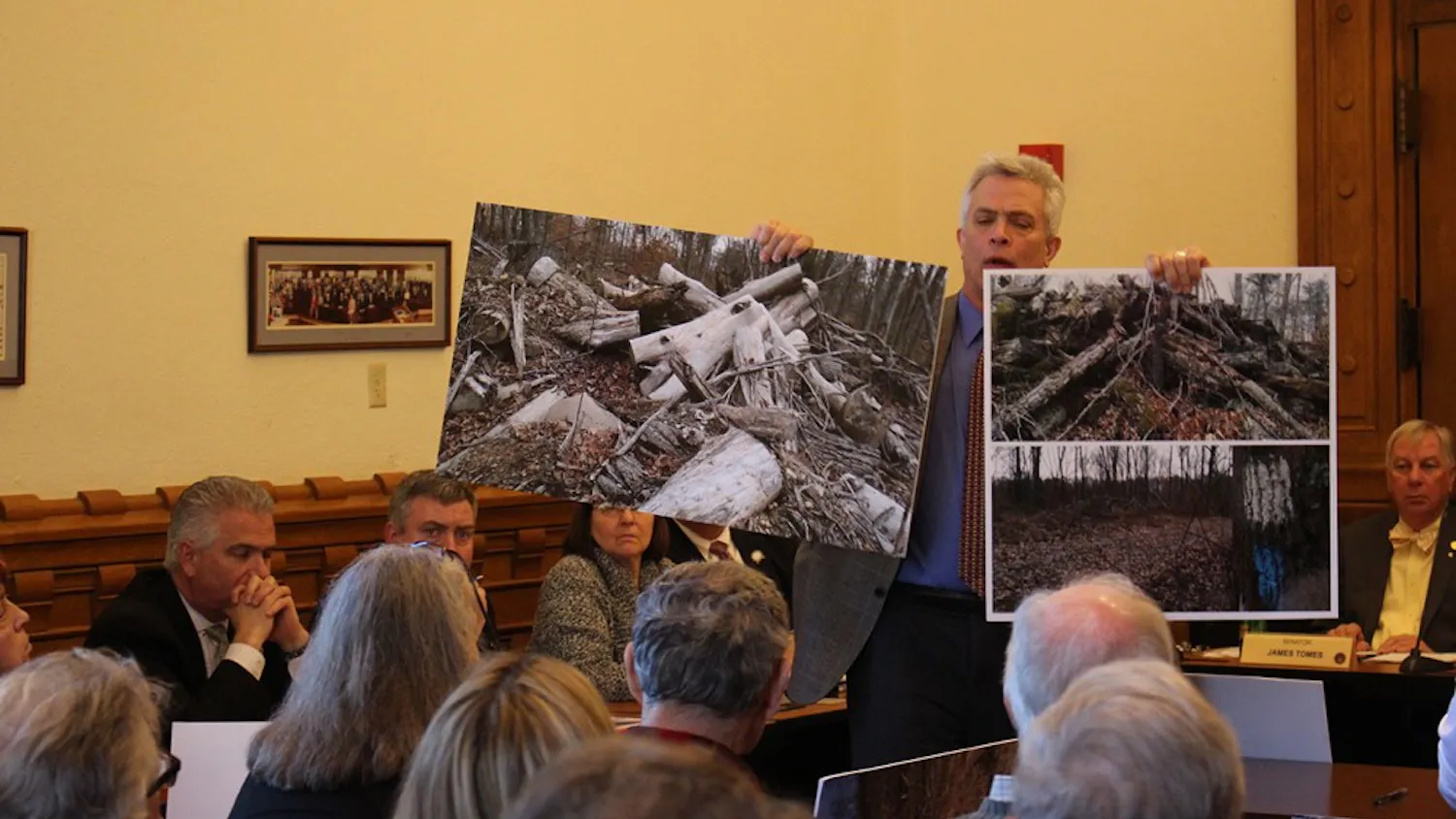 Jeff Stant, executive director of the Indiana Forest Alliance holds up posters depicting clearcuts. Stant testified in support of Senate Bill 420 at the Monday morning hearing.
