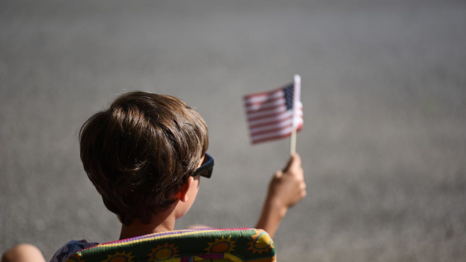 Lyle Henry, nine, waves an American flag during the 4th of July parade. Henry was one of hundreds of children attending the parade to watch and get candy.