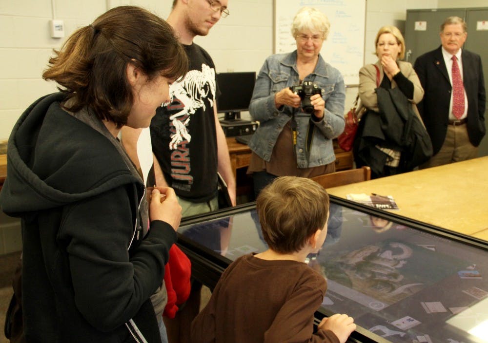 Visitors try out the visual interactive information about different kinds of fossils during the IU Paleontology event Saturday at Geology building.