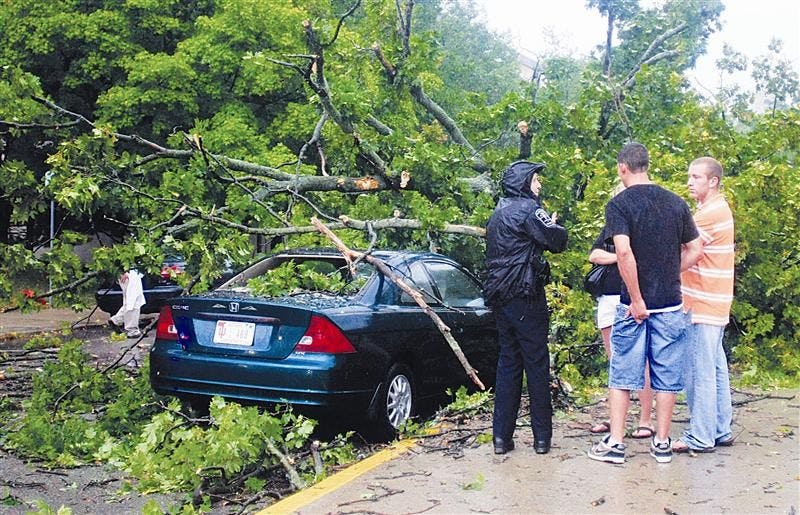Bloomington Police Department officer Amy Myers speaks with senior Tara Garrett and her two friends, Ross Gambrell and JD Daley, both seniors at IU-Purdue University Fort Wayne, after a tree fell on her car on Sunday near Sixth and Grant streets.