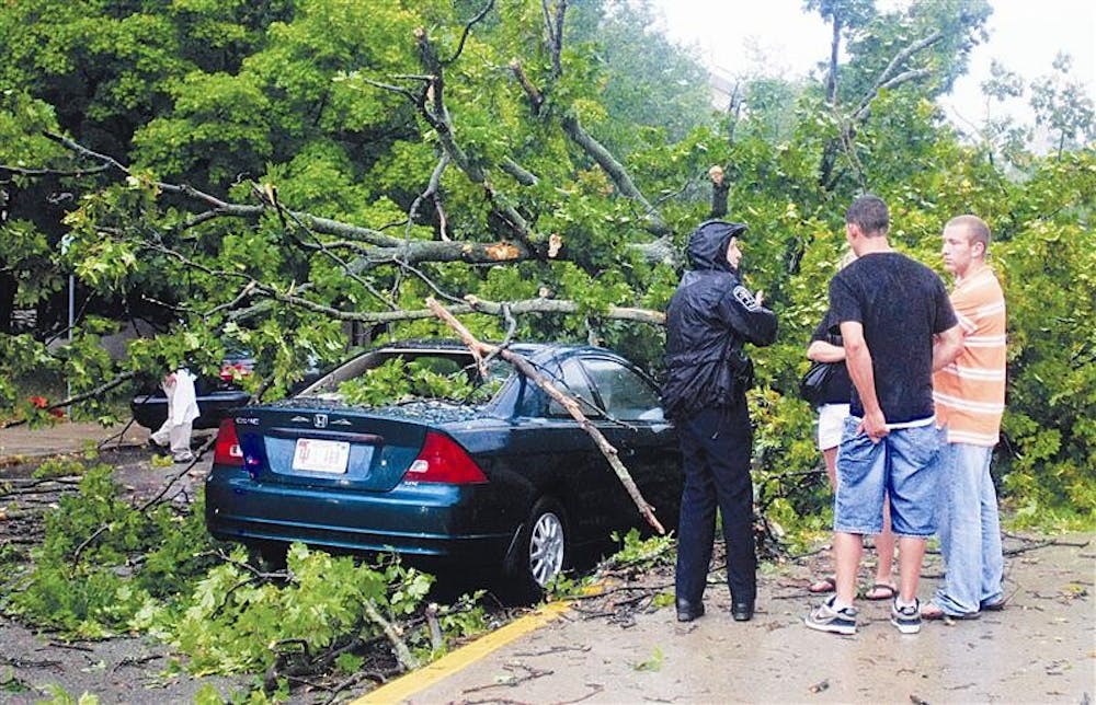 Bloomington Police Department officer Amy Myers speaks with senior Tara Garrett and her two friends, Ross Gambrell and JD Daley, both seniors at IU-Purdue University Fort Wayne, after a tree fell on her car on Sunday near Sixth and Grant streets.