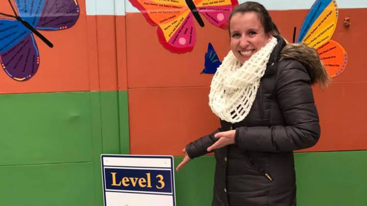 Childcare Coordinator Marcella Ettinger displays the level 3 achievement outside the daycare, in the courtyard at Middle Way House.