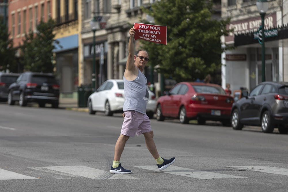 <p>A man holding a sign that reads &quot;Keep your theocracy off my democracy&quot; during a protst for reproductive rights crosses Walnut Street on June 24, 2022, across from the Monroe County Courthouse. During a panel hosted by IU on Monday, multiple experts agreed Indiana lawmakers will likely ban abortion.</p>