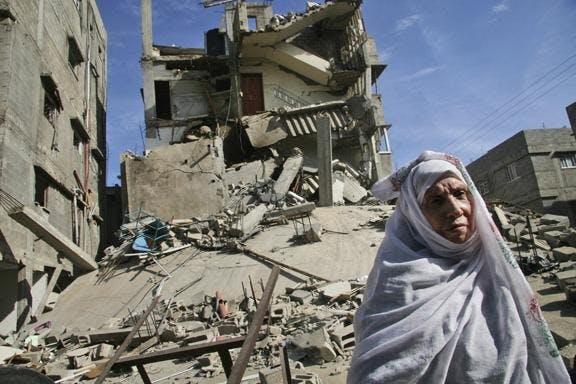 A Palestinian woman stands on the rubble of a destroyed building after an Israeli airstrike Wednesday in Gaza City. Two and a half weeks of Israel's fierce assaults on Gaza's Hamas rulers have destroyed at least $1.4 billion worth of buildings, water pipes, roads, power lines and other assets, independent Palestinian surveyors say. 