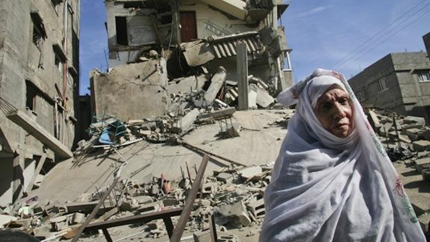 A Palestinian woman stands on the rubble of a destroyed building after an Israeli airstrike Wednesday in Gaza City. Two and a half weeks of Israel's fierce assaults on Gaza's Hamas rulers have destroyed at least $1.4 billion worth of buildings, water pipes, roads, power lines and other assets, independent Palestinian surveyors say. 