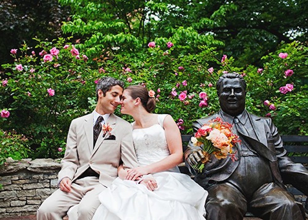 Katie Yoder and her new husband sit next to the statue of Herman B. Wells. Wendi Chitwood, their photographer, frequently incorporates IU Bloomington landmarks into her photos.
