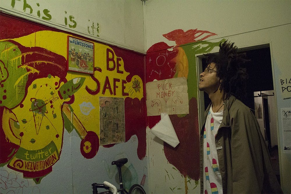 Resident Jeron Braxton reads some of the writing on the colorfully painted wall of the Velvet Onion. The house has become a philanthropic place where shows are for charities.