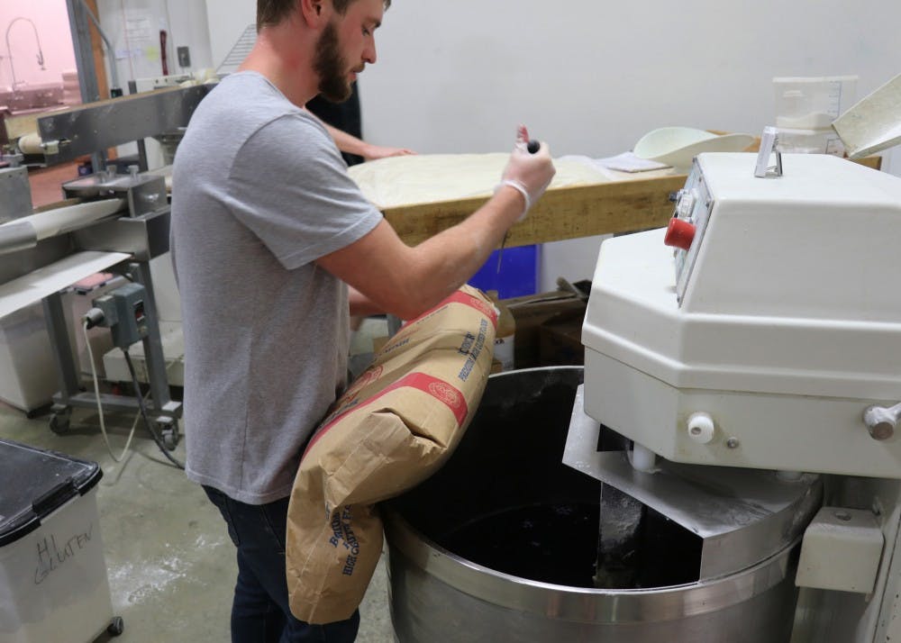 Production manager Tritan Ratts slices open a bag of all-purpose flour and pours it into the mixer. Bloomington Bagel Company opened in 1996 and now has four locations throughout Bloomington.