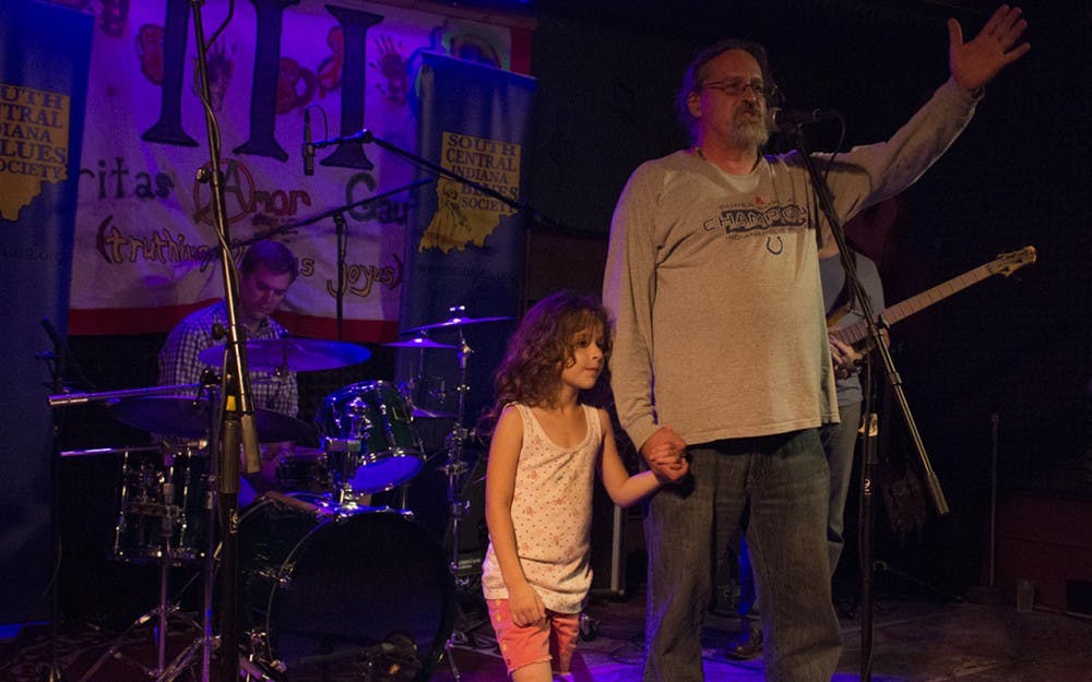 Joe Estivill, owner of Player’s Pub, stands on the stage of the pub with his daughter, Marie Estivill-Kilmer, 7, to address the crowd of people who rallied in support at Player’s Pub Tuesday night. He thanked customers for their support and said that he hopes to keep the pub going. 