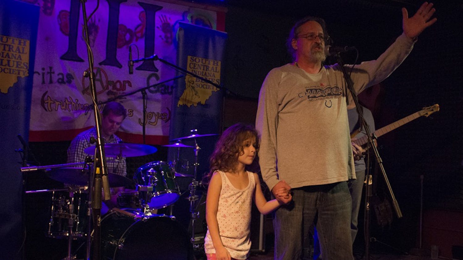 Joe Estivill, owner of Player’s Pub, stands on the stage of the pub with his daughter, Marie Estivill-Kilmer, 7, to address the crowd of people who rallied in support at Player’s Pub Tuesday night. He thanked customers for their support and said that he hopes to keep the pub going. 
