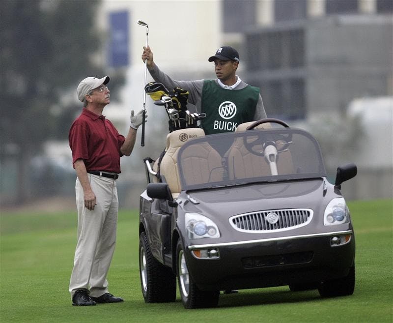 Tiger Woods pulls a club for John Abel while caddying on the 10th hole of the South Course on Monday at Torrey Pines in San Diego. Abel, from West Berlin, New Jersey, won a contest that entitled him to have Tiger Woods caddie for him.
