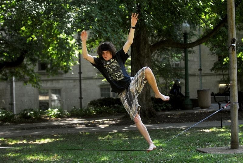 IU freshman Bryce Ledbetter tries to hold his balance on a slackline Thursday afternoon in front of the Collins Living-Learning Center. Slacklining is different from tight rope walking because the nylon webbing is strung at a much lower tension.