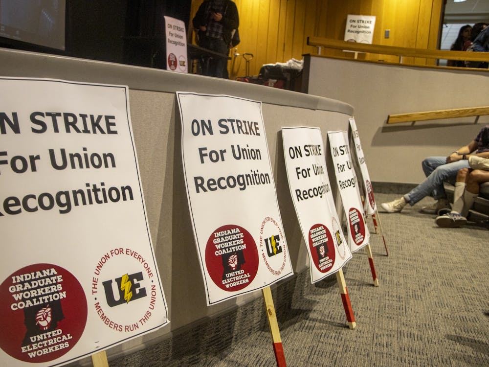 Signs are laid in front the auditorium stage at an in-person vote for the graduate students to go on strike April 10, 2022﻿, at the Monroe County Public Library. The Indiana Graduate Workers Coalition-United Electrical Workers held two Zoom meetings to talk about the strike Wednesday.