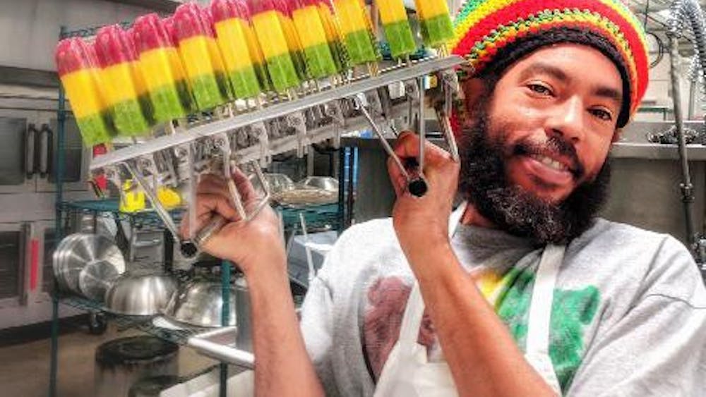 Iuri Santos, owner of the Rasta Pops cart, poses with some of his creations. Santos, a local businessman from Brazil, makes popsicles based on flavors in his home country.