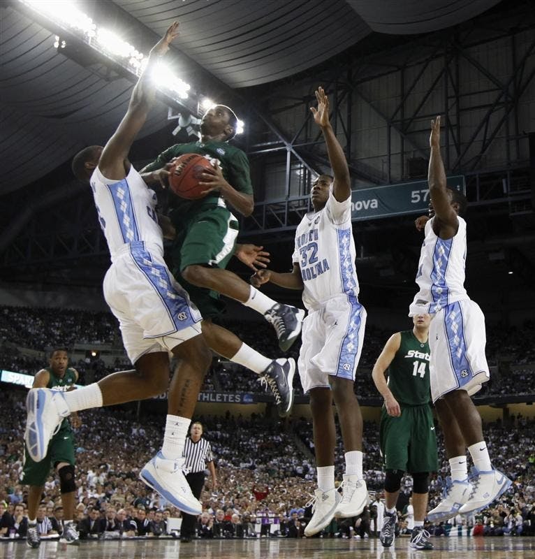 Michigan State's Kalin Lucas tries to drive to the basket under pressure from North Carolina players Deon Thompson, Ed Davis and Ty Lawson in the first half of the championship game at the men's NCAA Final Four college basketball tournament Monday in Detroit.  