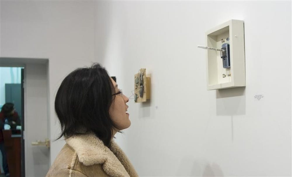 Shu-Mei Chan Evans, Bloomington resident and co-founder of the Bloomington Clay Studio, looks at a piece of Jeremy Kennedy's "4 Cell" Installation Friday evening at the McCalla Building. The exhibit's focus was the artist's obsession with materialism.
