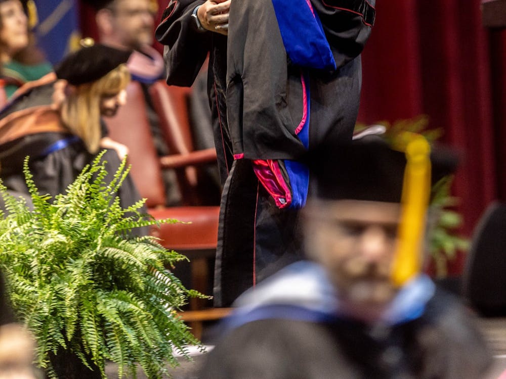 A graduate walks across stage with her doctoral hood in hand May 6, 2022, in Simon Skjodt Assembly Hall. IU President Pamela Whitten and Provost Rahul Shrivastav spoke at the ceremony.
